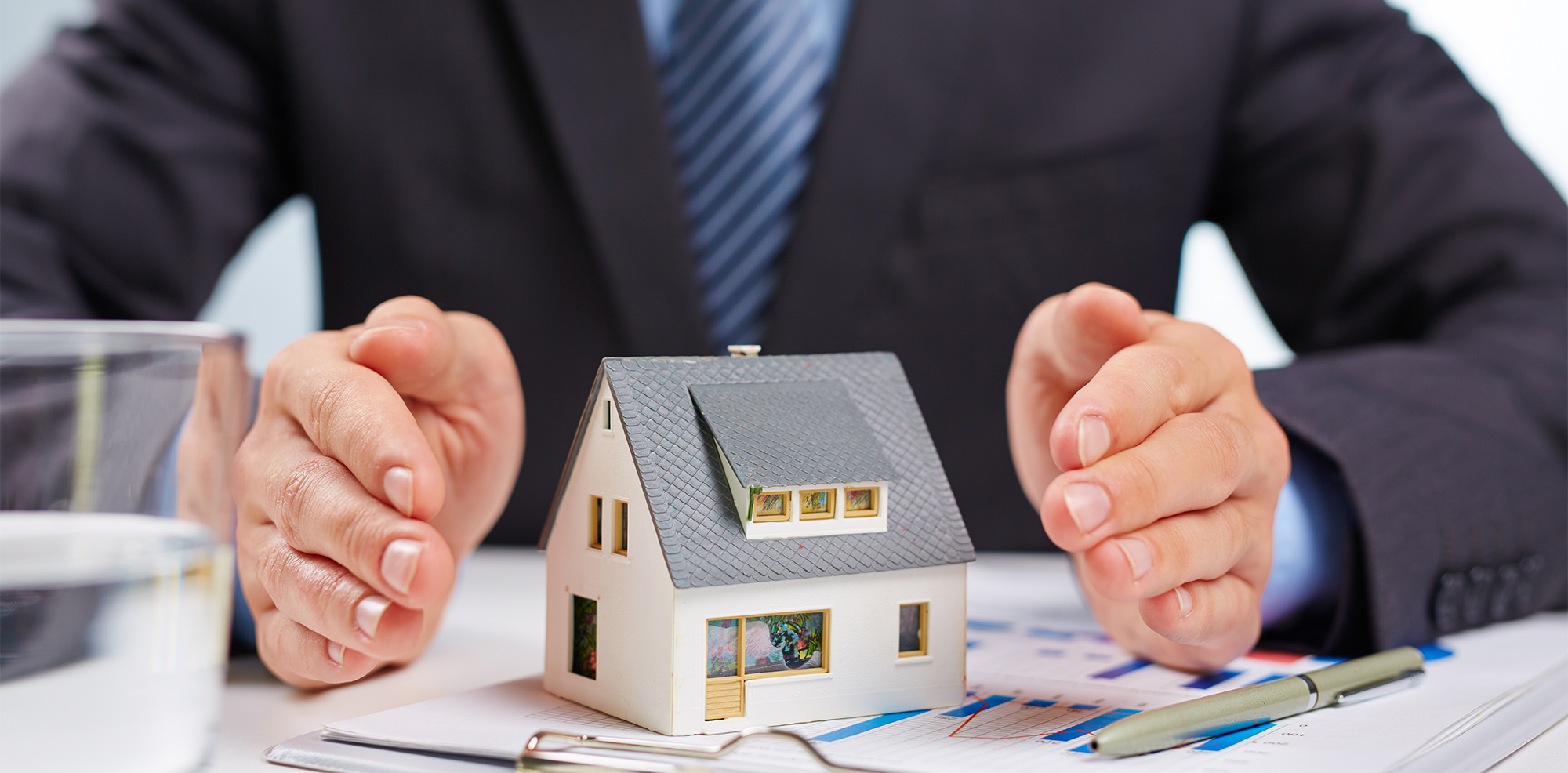 Business man's hands surrounding a house